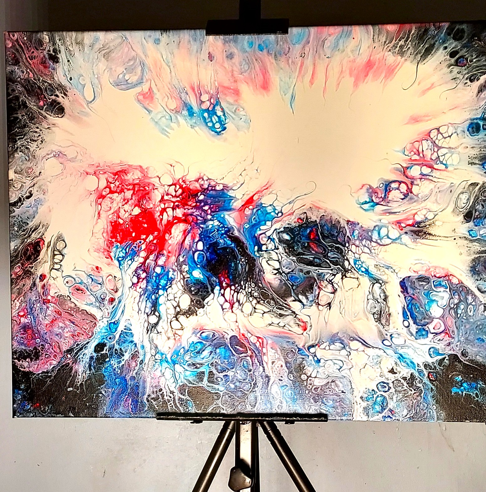An abstract fluid art painting in blue, white, and red.